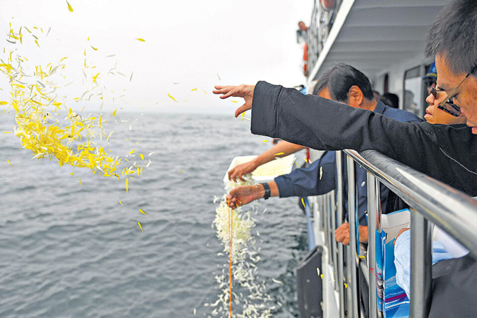 La viuda de Liu Xiabo (der.) tira pétalos de flores al mar durante la ceremonia. (Fuente: AFP)