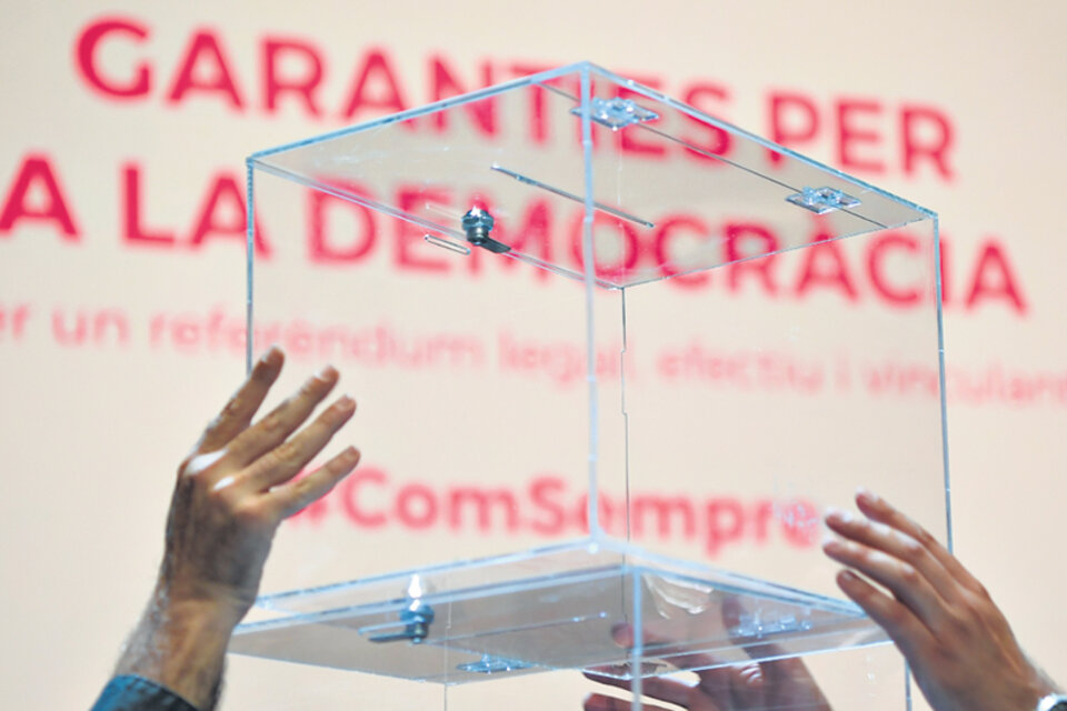 Diputados del Parlamento catalán sostienen una urna de vidrio durante la presentación.