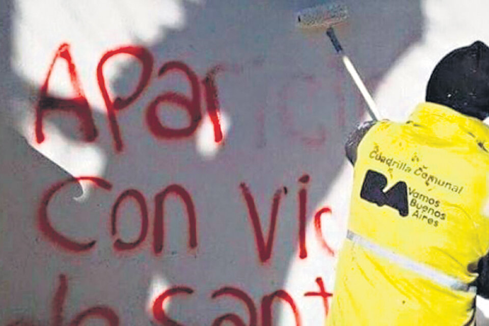 Un trabajador de la ciudad limpia pintadas que piden por la aparición de Santiago Maldonado.