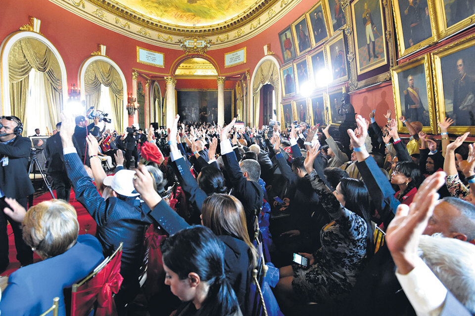 Miembros de la Asamblea Nacional Constituyente levantan sus manos durante su instalación en el Congreso venezolano. (Fuente: AFP)