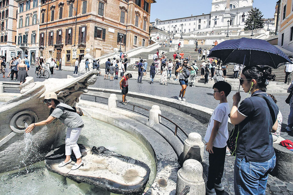 Los turistas se refrescan en la fuente Barcaccia, en la plaza España, en una Roma de calor agobiante. (Fuente: EFE)