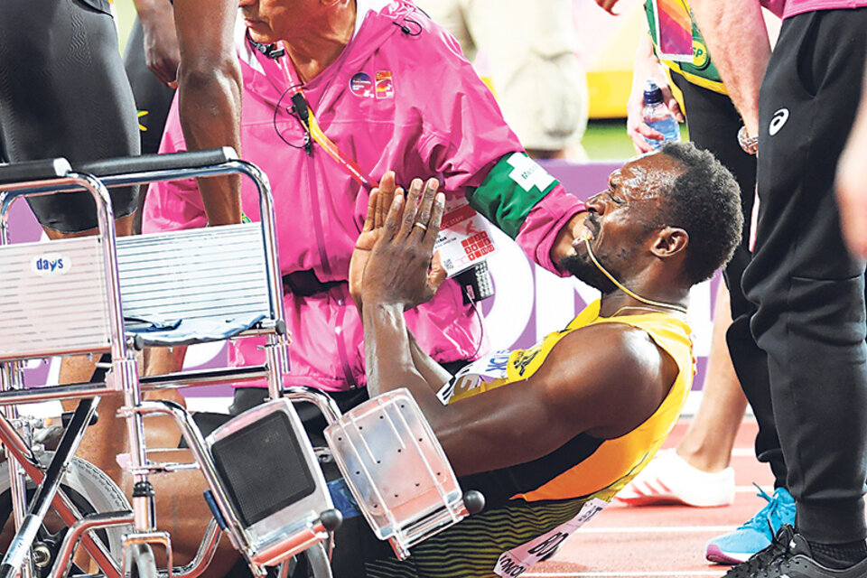 Usain Bolt recibe atención médica tras caer lesionado en la pista del Estadio Olímpico.