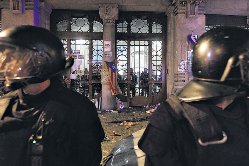 Policías catalanes observan mientras miembros de la Guardia Civil española allanan el ministerio de Economía del gobierno de Cataluña en Barcelona. (Fuente: EFE)