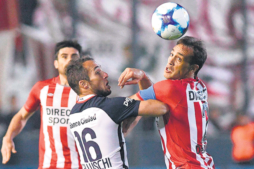 Belluschi, autor del tanto de San Lorenzo, disputa el balón con Desábato. (Fuente: Télam)