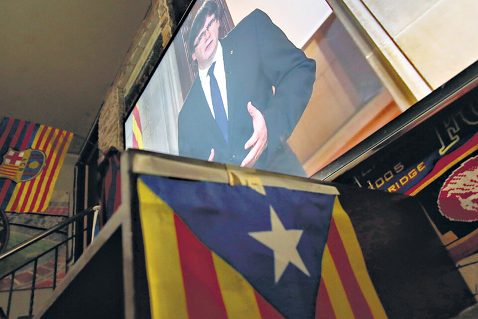 La pantalla gigante de un bar de Barcelona muestra la imagen de Puigdemont dando un mensaje a los catalanes. (Fuente: AFP)