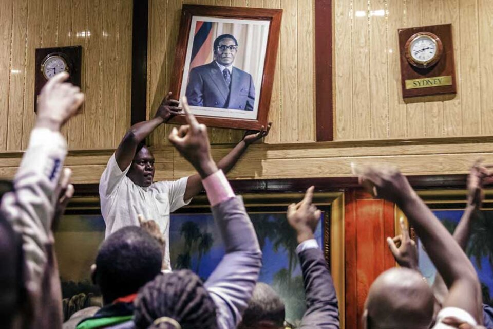 Manifestantes descuelgan el retrato de Mugabe del Centro de convenciones de Harare (Fuente: Jekesai NJIKIZANA / AFP)