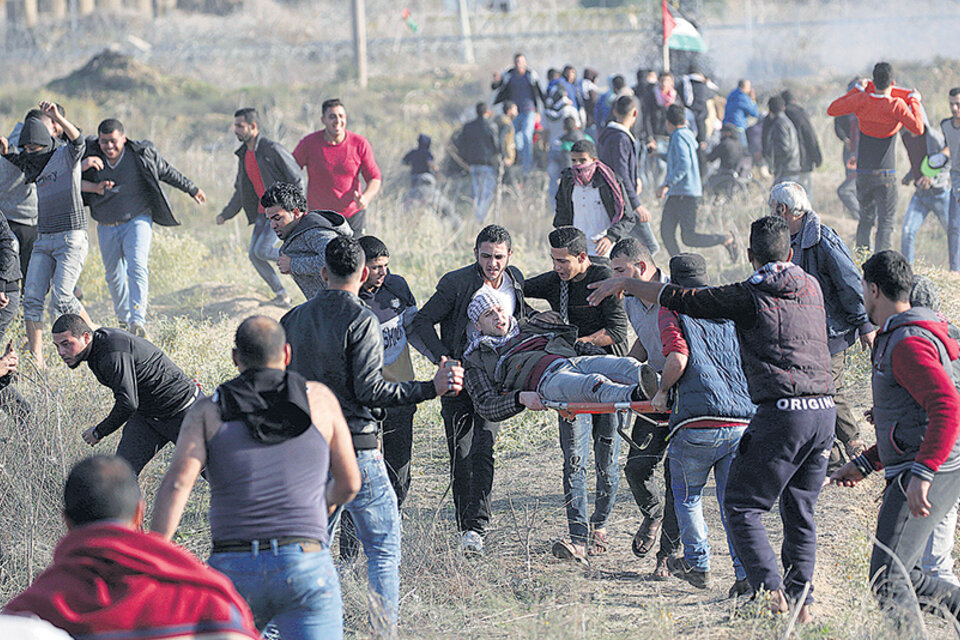 Manifestantes palestinos cargan con un herido durante un enfrentamiento con soldados israelíes en la frontera este de Gaza.