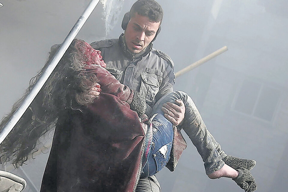 Un voluntario de la defensa civil levanta a una niña herida tras un bombardeo en Guta. (Fuente: AFP)