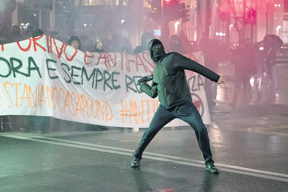 Un manifestante antifascista arroja una botella contra el cordón policial en Turín. (Fuente: AFP)