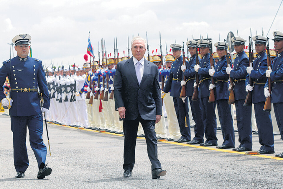 El presidente de facto Michel Temer inspecciona tropas en el aeropuerto al llegar a una reunión del Consejo Militar de Defensa en Brasilia. (Fuente: EFE)