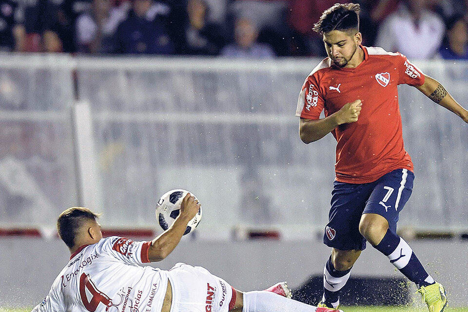 Martín Benítez intenta pasar la pelota por sobre el cuerpo de Kevin Mac Allister. (Fuente: Télam)