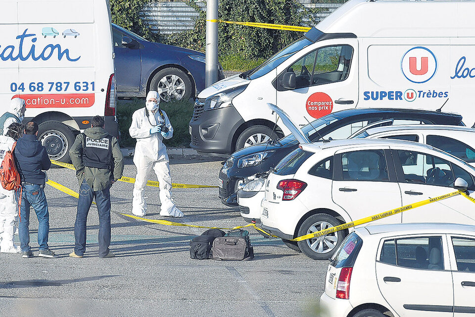 Peritos forenses inspeccionan en Trebes al auto de terrorista (el del capó levantado).