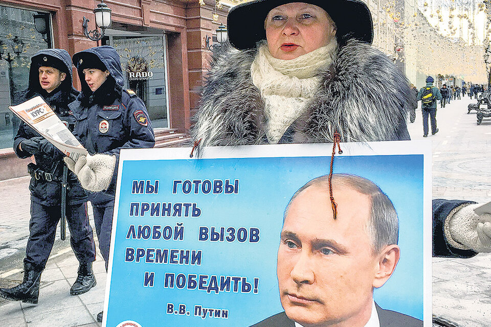 Una activista distribuye panfletos que promueven el voto a Putin ayer en el centro de Moscú, a horas de las elecciones. (Fuente: AFP)