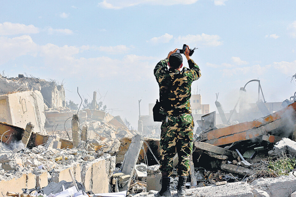 Un soldado sirio inspecciona las ruinas del edificio que era parte de un centro de investigación científica en Damasco. (Fuente: AFP)