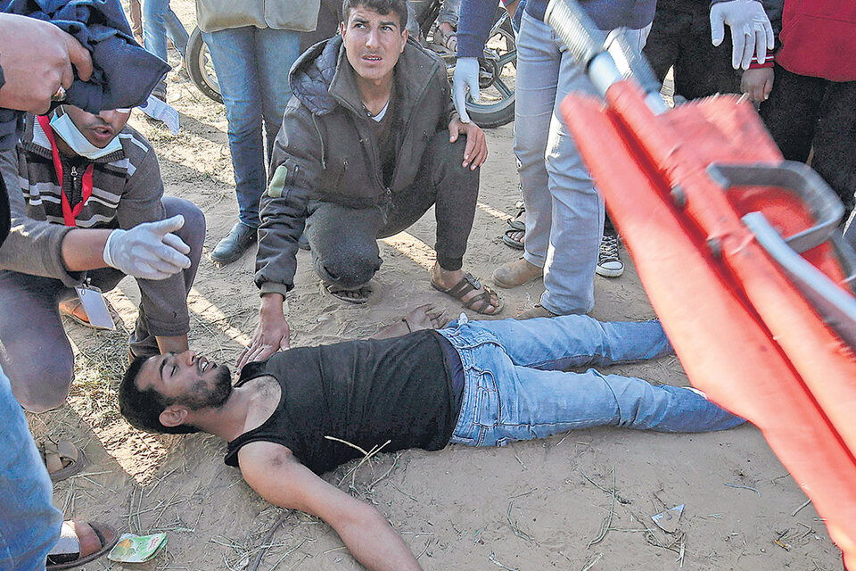 Manifestantes palestinos en la frontera con Gaza auxilian a un activista herido por la policía israelí.
