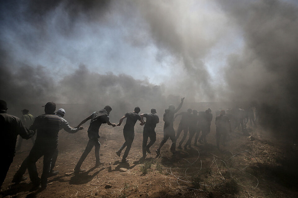 Manifestantes palestinos cargan contra la valla en la frontera mientras el ejército israelí los reprime. (Fuente: EFE)