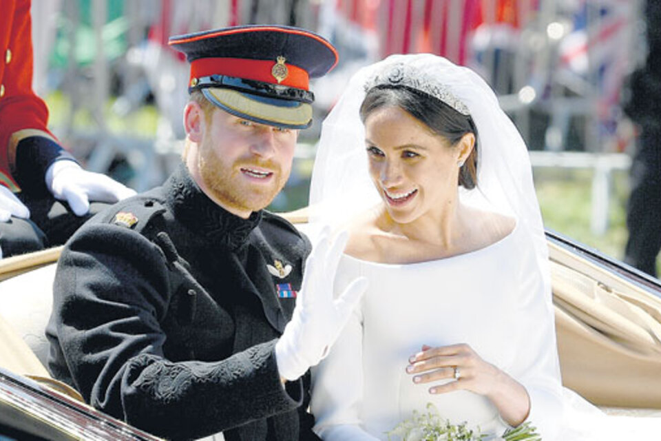 Ya casados y convertidos en los duques de Sussex (regalo de la reina Isabel), Harry y Meghan saludan desde un carruaje descubierto. (Fuente: AFP)