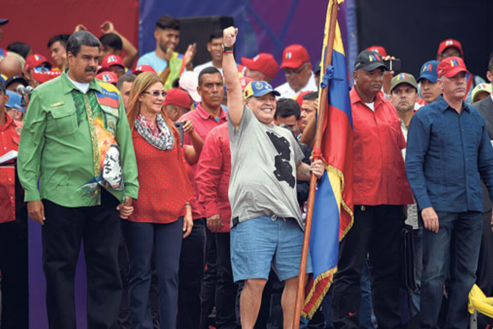 Maduro, de la mano de su esposa Cilia Flores, mira a Maradona, que saluda a la multitud puño en alto y bandera en mano durante el cierre de campaña. (Fuente: AFP)