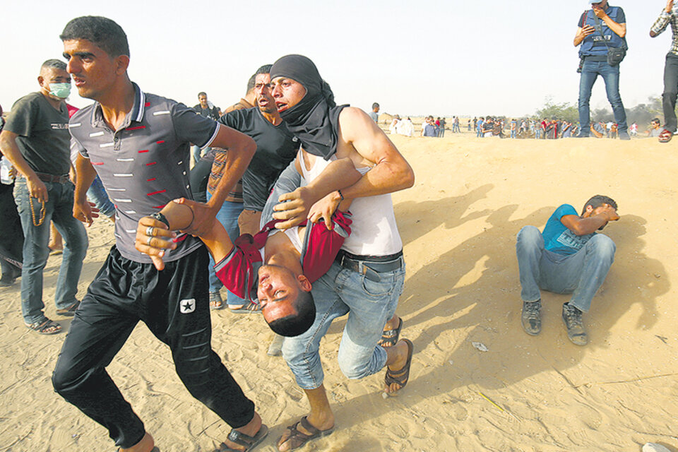 Manifestantes palestinos cargan con un herido durante una protesta en el límite de la Franja de Gaza. (Fuente: AFP)