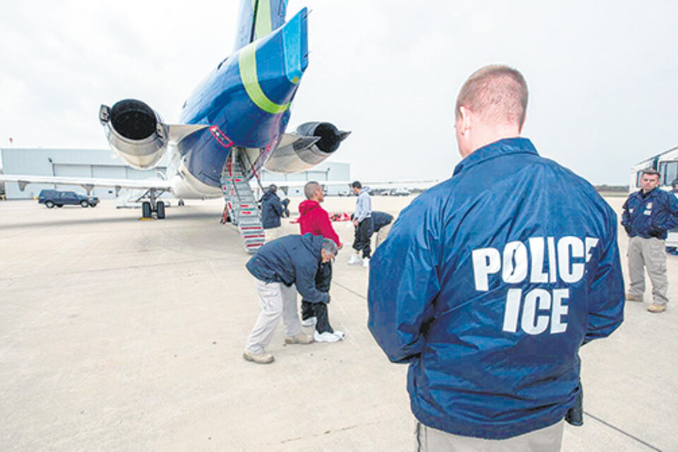 Un agente migratorio de EE.UU. controla mientras inmigrantes abordan un avión de la agencia para ser deportados.
