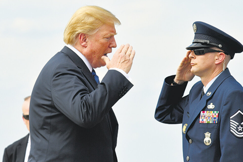 Trump saluda a un escolta en la base aérea Andrews antes de abordar el avión presidencial.