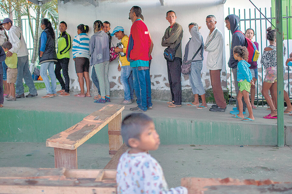 Inmigrantes venezolanos hacen fila para desayunar en una parroquia en Pacaraima, estado de Roraima, Brasil. (Fuente: AFP)