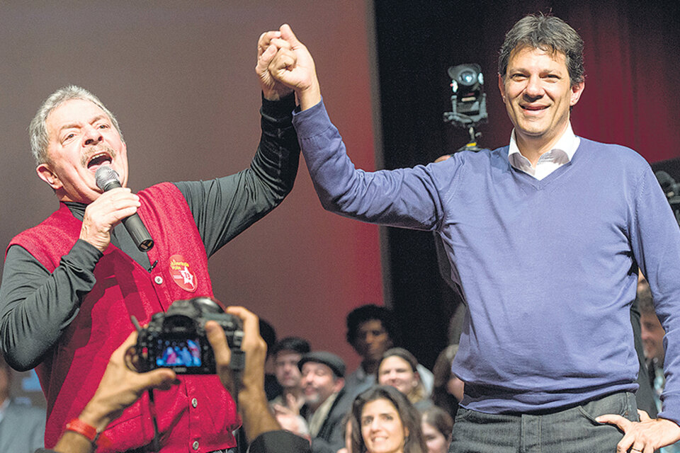 Lula alzando el brazo de Haddad durante un acto en San Pablo, poco antes de que el líder del PT fuera arrestado. (Fuente: AFP)