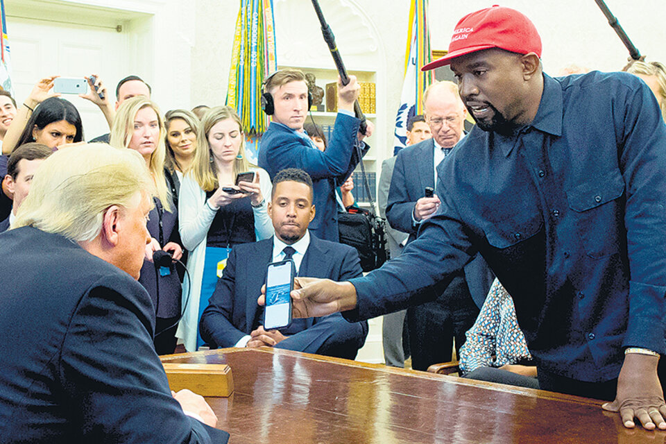El rapero West le muestra una foto de su celular a Trump. (Fuente: EFE)
