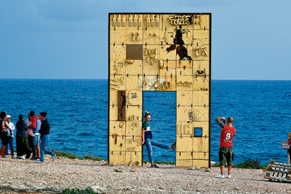 Turistas sacan fotos en “La puerta de Europa”, un monumento a los migrantes. (Fuente: AFP)