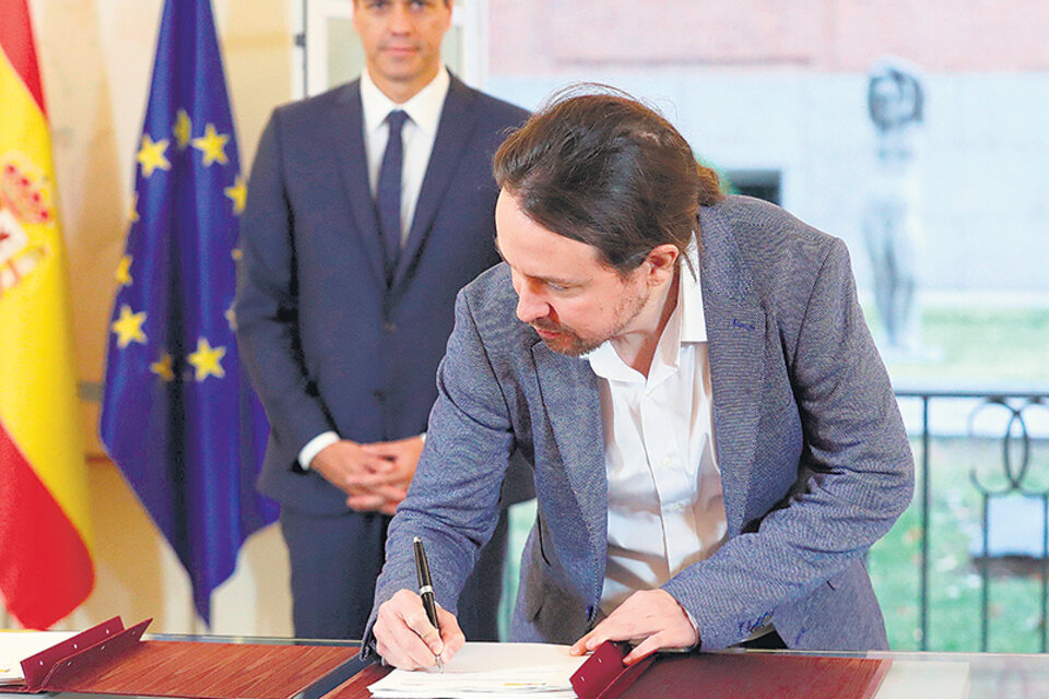 Iglesias firma el acuerdo bajo la atenta mirada de Sánchez ayer en Madrid. (Fuente: EFE)