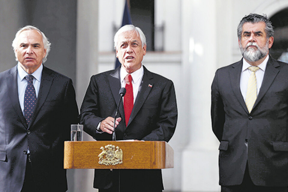 Flanqueado por el ministro y el secretario de Interior, Piñera anuncia la dimisión del jefe de Carabineros. (Fuente: EFE)