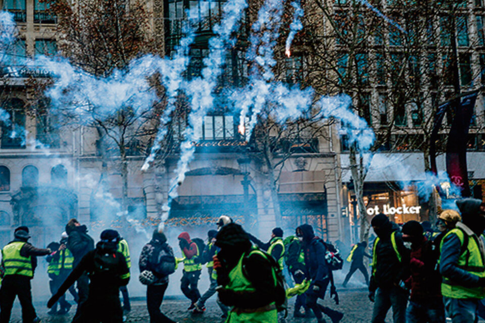 Chalecos amarillos resisten el gas lacrimógeno en los Champs-Elysées. (Fuente: AFP)