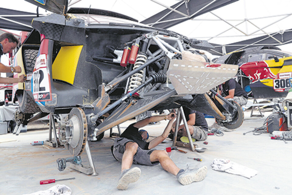 Los mecánicos trabajando en el Peugeot 3008 de Sebastien Loeb. Una rutina que se dio en cada campamento. (Fuente: EFE)