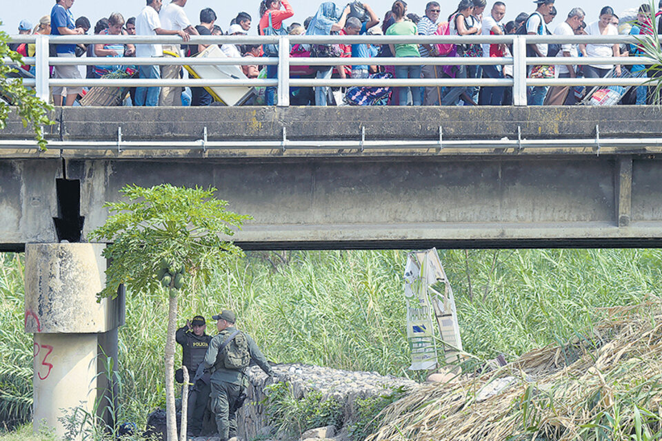 Policías vigilan el puente internacional Simón Bolívar que une Cúcuta con Táchira, mientras una marea humana cruza. (Fuente: AFP)