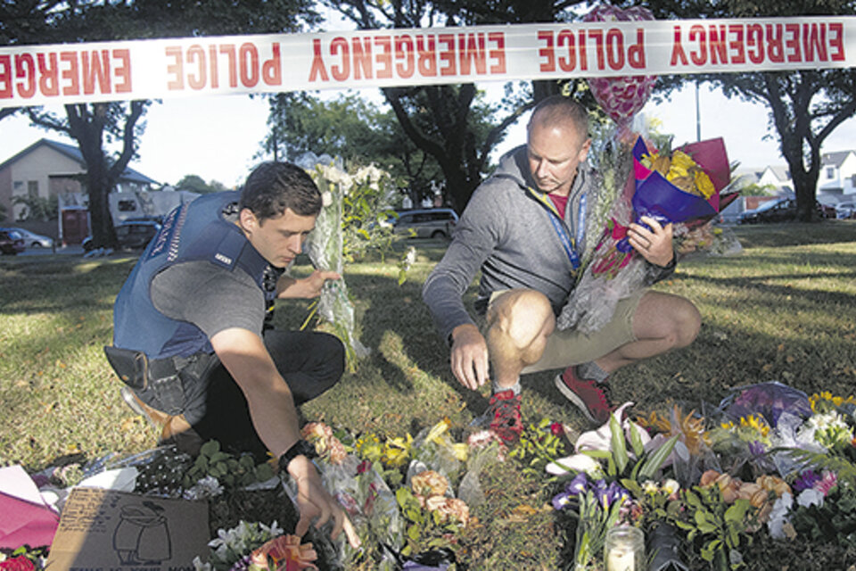 Policías llevan flores al altar improvisado frente a la mezquita de Linwood en Christchurch, Nueva Zelanda. (Fuente: AFP)