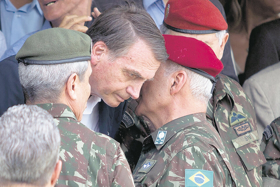 El general del Ejército Baptista Pereira le habla al oído a Bolsonaro durante una ceremonia en Río de Janeiro.