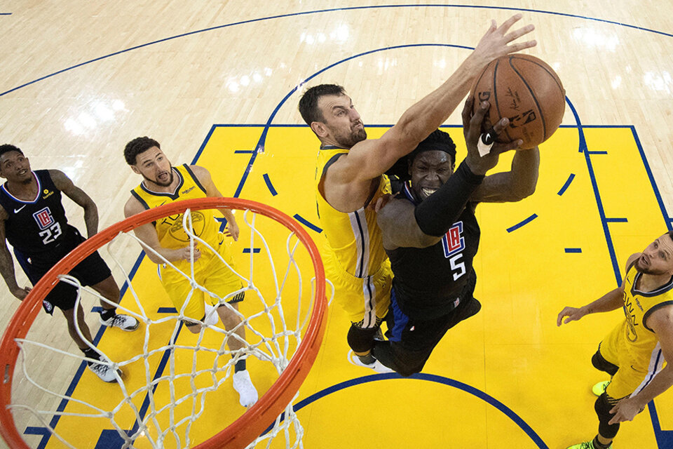 Montrezl Harrell intenta imponerse a la marca del australiano Andrew Bogut. (Fuente: EFE)