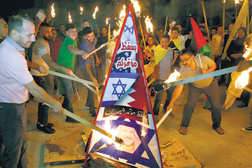 Palestinos queman una figura con la bandera de Israel y la imagen del rey de Baréin en Hebron, Cisjordania.