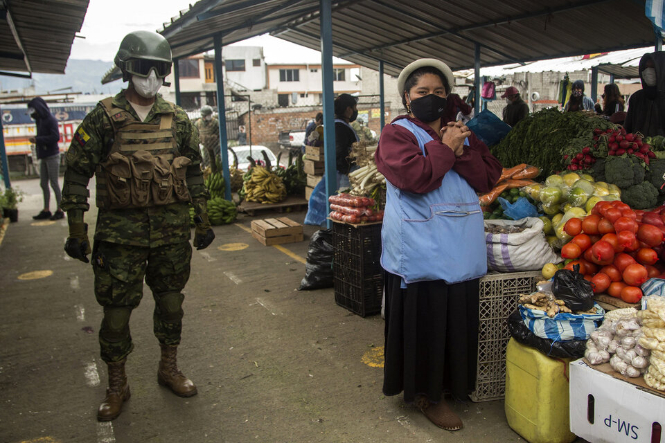 Un soldado patrulla un mercado en Quito para asegurarse de que se cuplan las restricciones. (Fuente: AFP)