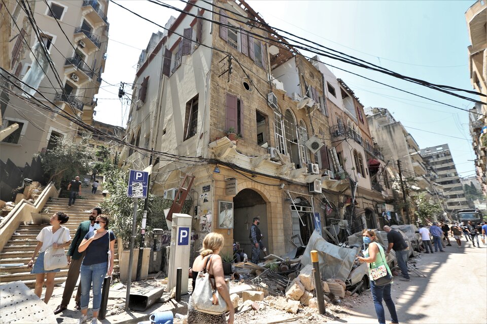 Un grupo de personas camina delante de edificios dañados por las explosiones en el barrio Achrafyeh Rmeil de Beirut. (Fuente: EFE)