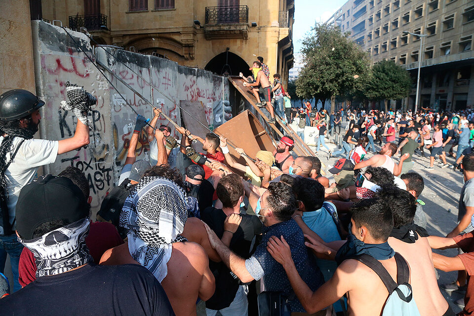 Manifestantes cargan contra una valla frente al Parlamento de Beirut. (Fuente: EFE)