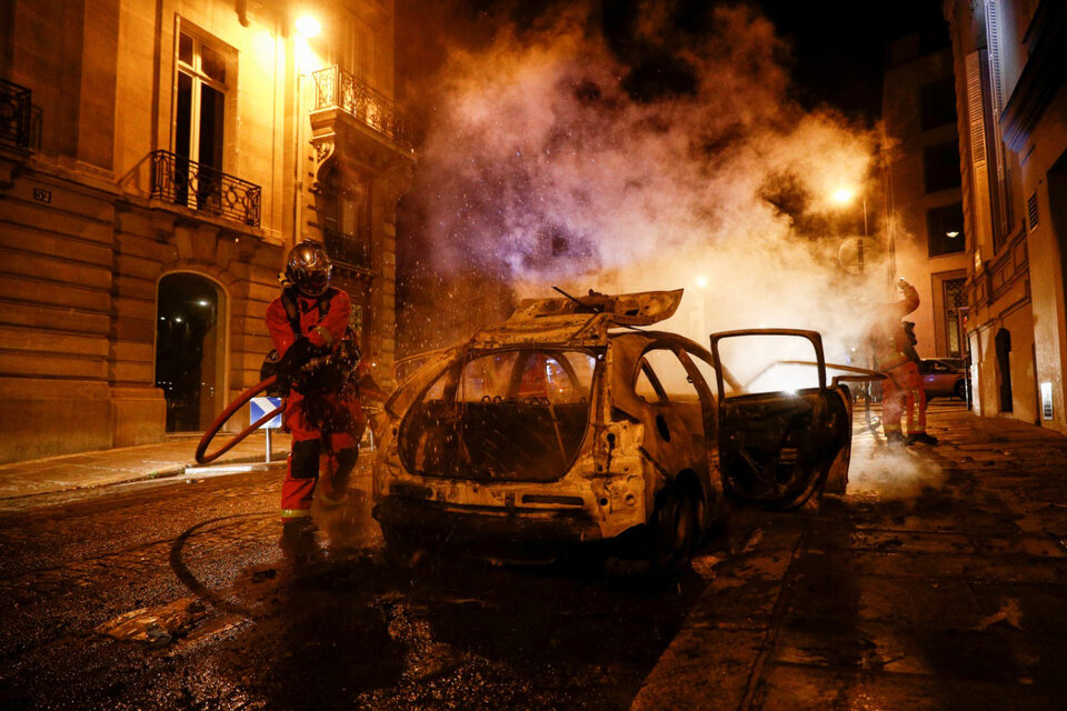 Un bombero apaga el incendio intencional de un automóvil. (Fuente: AFP)