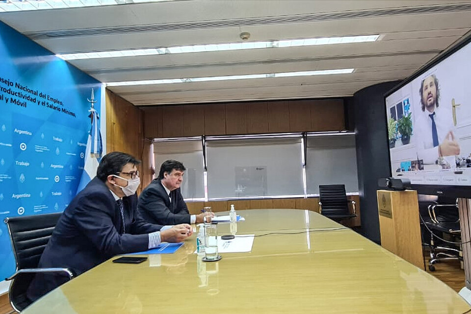 El ministro de Trabajo, Claudio Moroni, escucha al jefe de Gabinete, Santiago Cafiero, durante el encuentro.