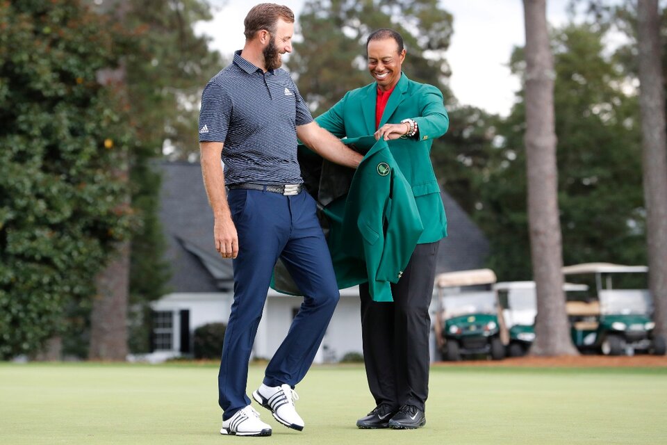 Tiger Woods le entregó la mítica chaqueta verde a Dustin Johnson, el campeón récord. (Fuente: EFE)