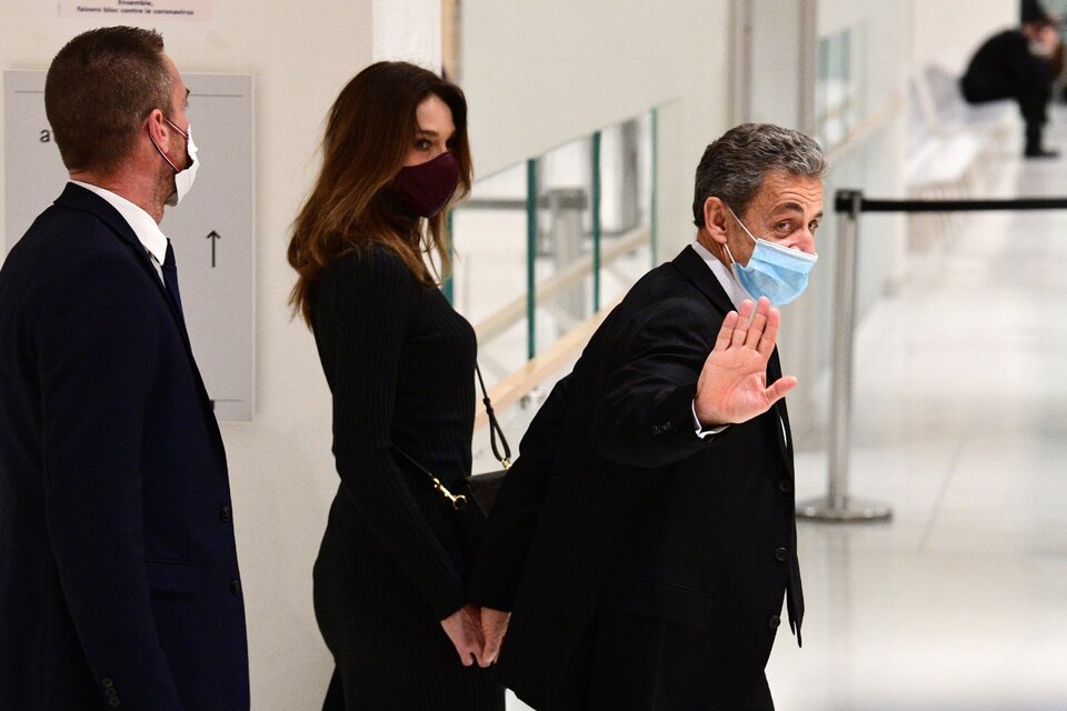 Sarkozy saluda al salir del juzgado junto a su esposa Carla Bruni.
