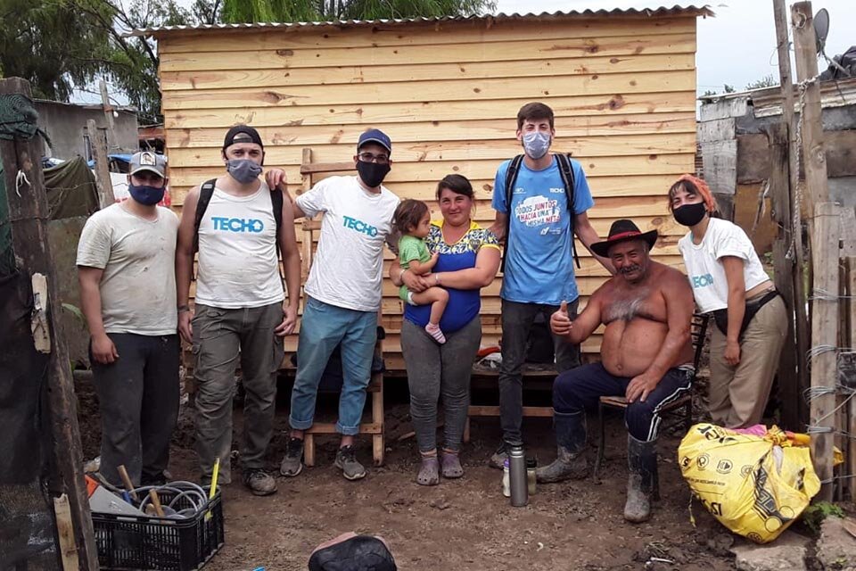 Vecinos y voluntarios de la ong Techo  junto a una vivienda construida.