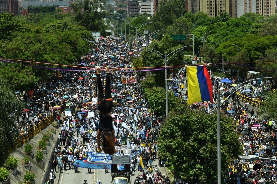 Un manifestante colgado de un cable y miles más marchando en contra de Duque en Medellín (Fuente: AFP)
