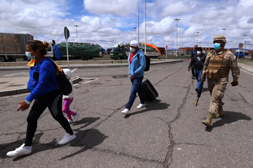 Un Carabinero chileno escolta a un grupo de migrantes en Colchane, cerca de la frontera con Bolivia. (Fuente: AFP)
