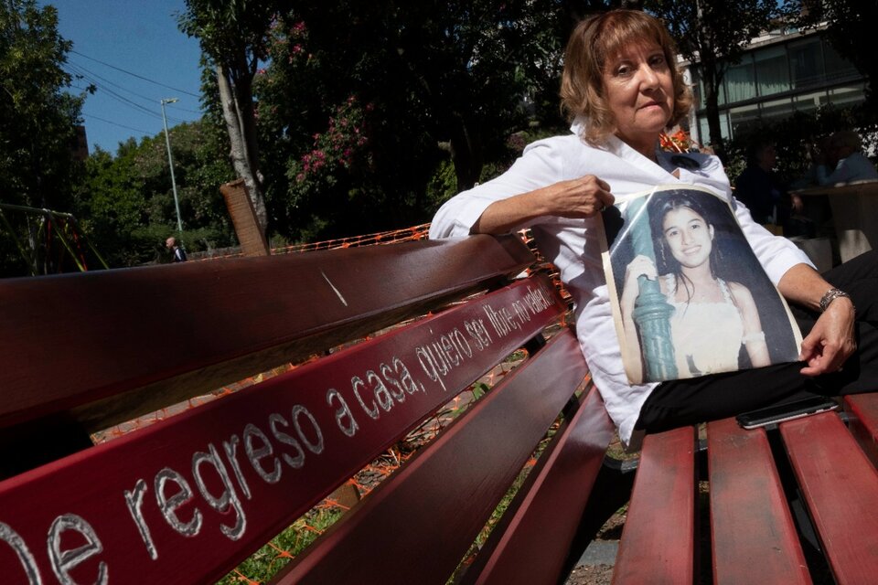 La mamá de la adolescente, en el banco rojo que se puso en el lugar del crimen. (Fuente: Télam)