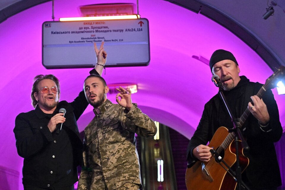 Bono, cantando junto con un soldado ucraniano en el concierto sorpresa que brindó con The Edge en la estación de subte de Khreschchatyk, en Kiev (Ucrania). Imagen: Sergei Supinsky / AFP